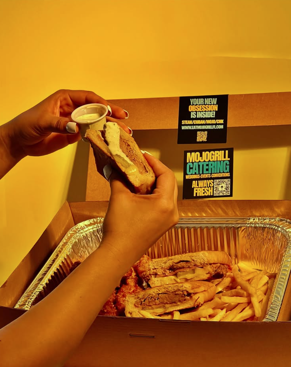 Catering box open with Cuban sandwich and fries
